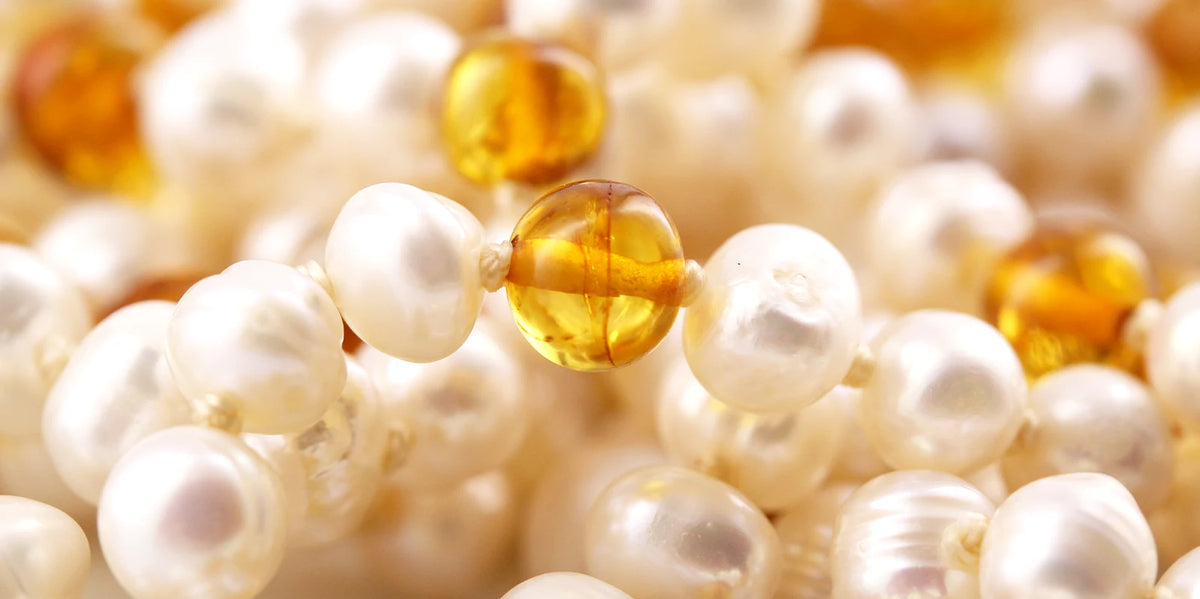 Close-up of pearls and amber beads on a light background